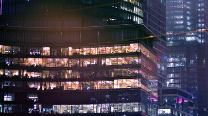 Fototapeta na wymiar Corporate building at night - business concept. Glass wall office building .Modern office windows of skyscraper glowing at night.