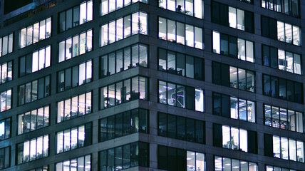 Fototapeta na wymiar Corporate building at night - business concept. Glass wall office building .Modern office windows of skyscraper glowing at night.