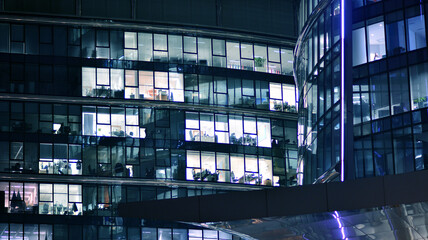 Corporate building at night - business concept. Glass wall office building .Modern office windows of skyscraper glowing at night.