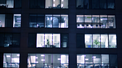 Corporate building at night - business concept. Glass wall office building .Modern office windows of skyscraper glowing at night.