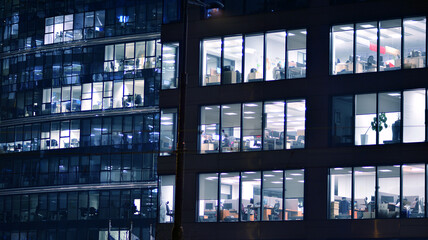 Corporate building at night - business concept. Glass wall office building .Modern office windows of skyscraper glowing at night.