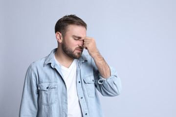 Young man suffering from headache on light background, space for text