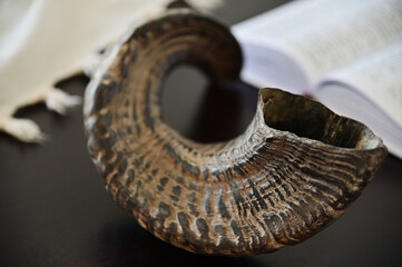Close up of Shofar (rams horn) Tallit and Jewish prayer book on a wooden table.