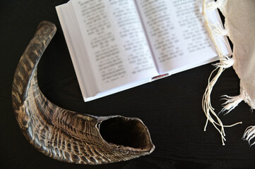 Above view of Shofar (rams horn) Tallit and Jewish prayer book on a wooden table.