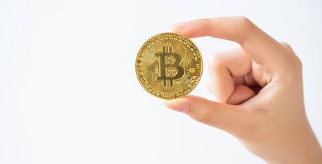 Fototapeta na wymiar Someone hand holding a golden Bitcoin token isolated on white background. Bitcoin is one of the popular cryptocurrency, a virtual currency or a digital currency.