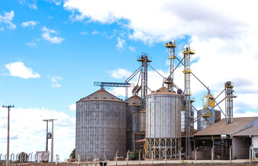 Fototapeta na wymiar Rural area with grain storage silos and blue sky with clouds.