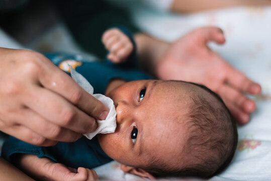 Mother Wiping Her Newborn Baby's Face With A Gauze.