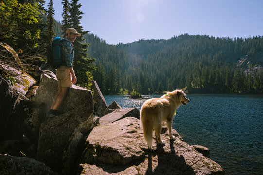Guy and his dog standing next to an alpine lake
