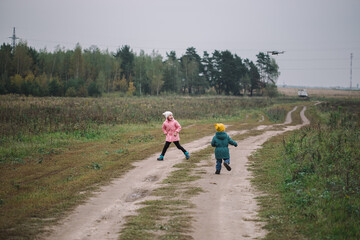 Obraz premium Children play in the field running from flying drone