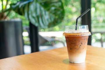 iced latte coffee in takeaway glass on table in coffee shop