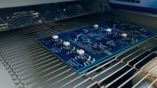 Thermal soldering of electronic elements on computer boards. Reflow soldering: Computer board with Mounted elements exits Electronics Industrial Furnace. 