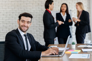 Positive businesswoman browsing laptop near multiethnic colleagues