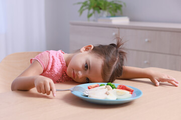 Cute little girl refusing to eat her breakfast at home