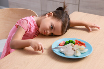 Cute little girl refusing to eat her breakfast at home