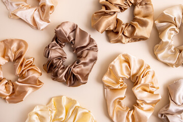 Collection of trendy silk elastic bands scrunchies on beige background. Diy accessories and hairstyles concept, luxury color
