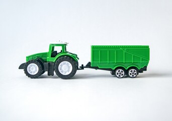 Toy green tractor with trailer on a white background