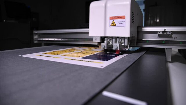 industrial plotter cuts a template on a cardboard packaging for products. real time shallow depth of field. Live camera