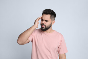 Young man suffering from headache on light background