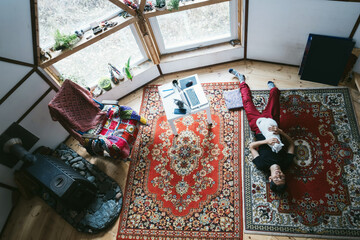 Young male freelancer resting lying on the floor with white cat in a vintage style domed house - Powered by Adobe