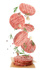 Fresh raw burger patties and seasonings falling on white background