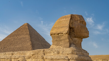 Ancient great Sphinx close-up. Head and face in profile against the blue sky. The Great Pyramid of...