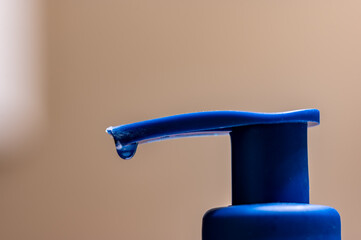 liquid soap dispenser pump with a single droplet suspended at the tip end ready to fall. 