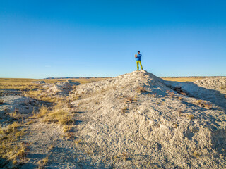 Fototapeta premium drone pilot with a tablet and radio controller at badlands in Colorado prairie, fall scenery aerial