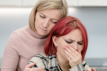 Careful mother hugs and calms her crying teen daughter home. Teenagers problem concept