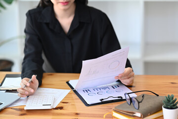 Cropped shot accountant checking financial documents and using calculator on office desk.