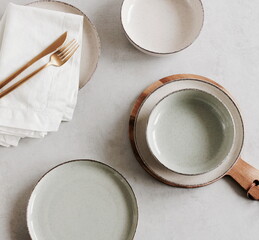 Modern ceramic tableware top view on beige table with copy space.  Trendy plates, cutlery and linen...