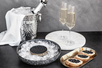 Black caviar in can on ice, caviar sandwich on golden plate, champagne in glass