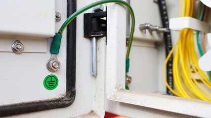 Yellow-green ground wire in a metal box. Gray metal box has a ground wire connected on the lid to...