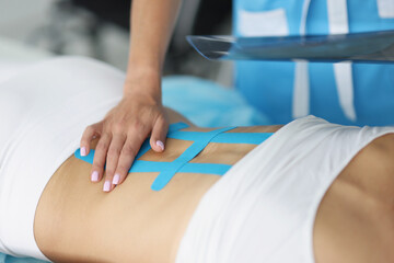 Doctor holding x ray of womans back and correct kinesiology tape