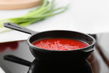 Frying pan with organic tomato sauce on stove in kitchen