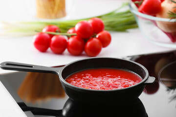 Frying pan with organic tomato sauce on stove in kitchen