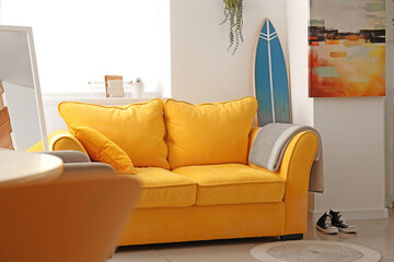 Interior of stylish modern room with surfboard and sofa