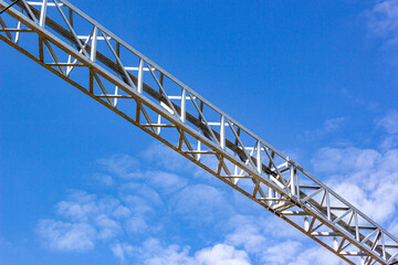 Steel truss made of metal corners against the blue sky. Structure of steel roof frame for building construction. Framework detail of metal bridge. Closeup bottom view