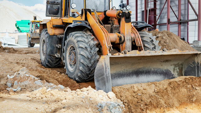 A powerful front loader on the construction site performs sanding. Moving soil with construction equipment. Excavation.