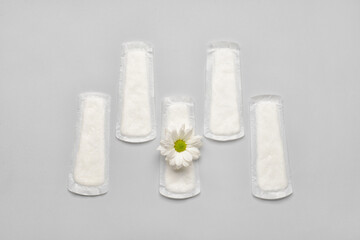 Menstrual pad and chamomile flower on light background