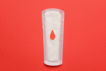 Menstrual pad and drawn blood drop on red background