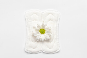 Fototapeta na wymiar Menstrual pads and chamomile flower on white background