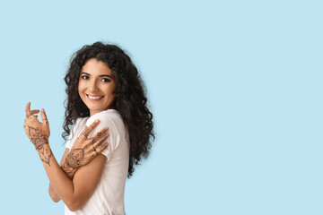 Beautiful Indian woman with henna tattoo on color background