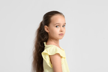 Portrait of cute little girl with ponytail on white background