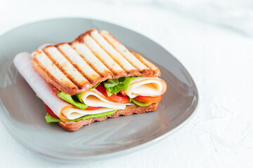Toast sandwich with gouda cheese and turkey ham filled with tomato and lettuce on a bright...