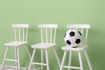 White chairs with soccer ball on color background