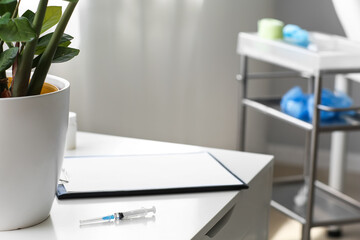Syringe and clipboard on shelf in medical office, closeup
