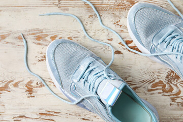 Pair of sportive shoes with untied laces on light wooden background, closeup - obrazy, fototapety, plakaty