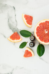 two glass bottles of capsli for medical and cosmetic use with citrus oil on a white marble table with juicy grapefruit.