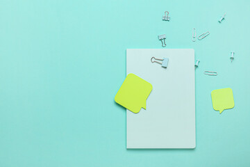 Notebook, pins, clips and sticky notes on color background