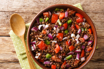 Delicious fresh green lentil salad with tomatoes, onions and chili peppers close-up in a plate on the table. horizontal top view from above